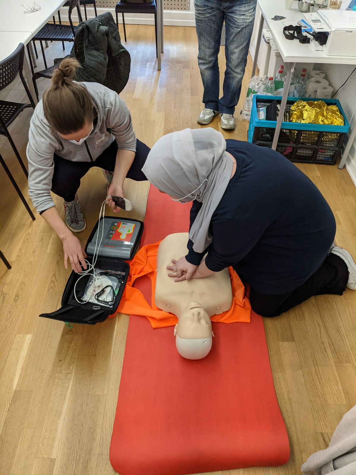 Students practising CPR with an AED trainer during a class