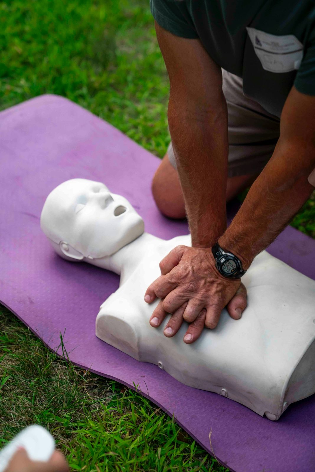 Hands performing chest compressions on a CPR training manikin