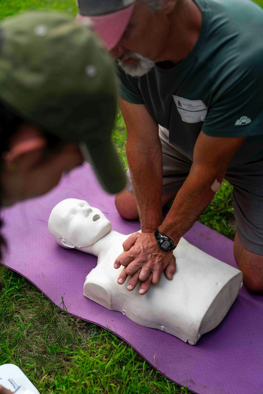 Instructor demonstrating hand placement for chest compressions outdoors